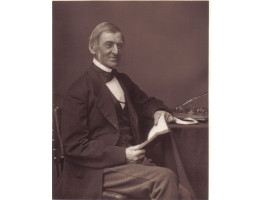 Portrait Photograph of  Emerson, looking right, seated at his desk, with an open book in his hands, by Elliott & Fry.